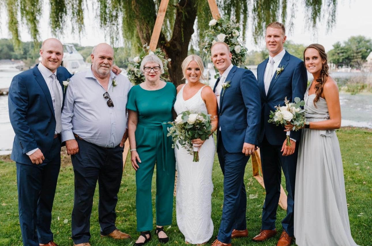 A joyful couple celebrates their wedding by the lake with family and friends.