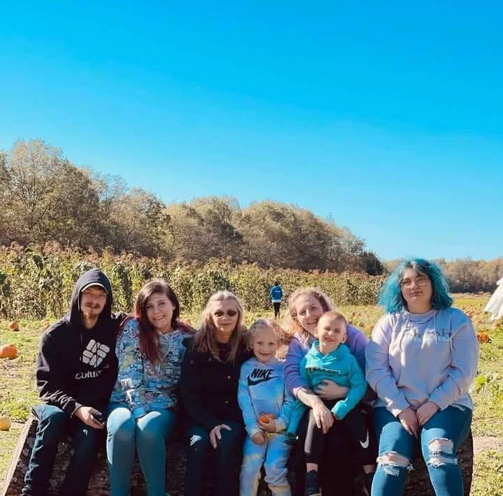 Several people gather in a pumpkin patch, enjoying a fun day among the autumn landscape.