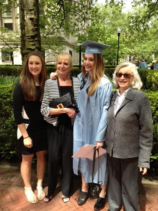 Family gathers in a park to celebrate a graduation, showcasing joy and pride among them.