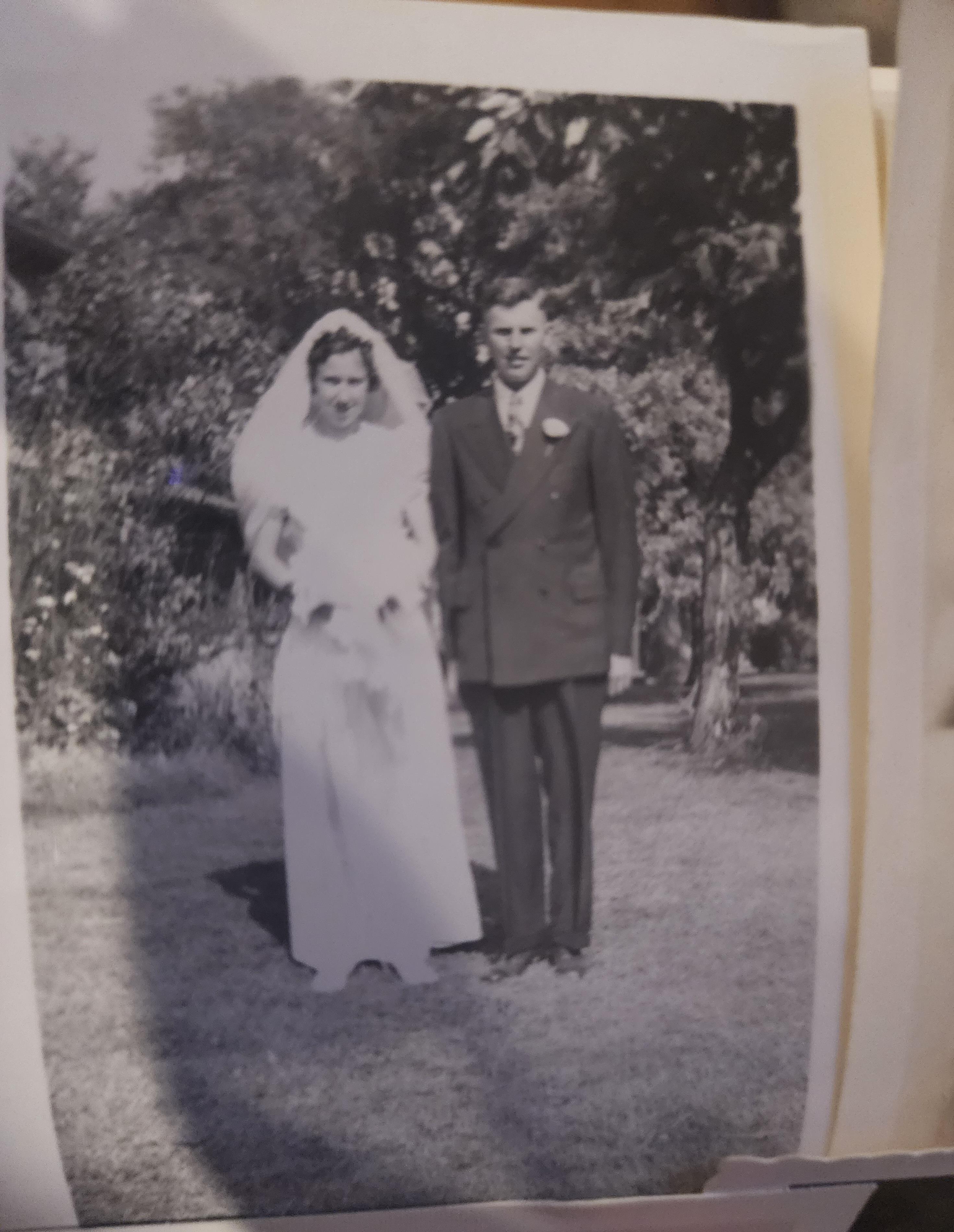 Celebrating love, a couple stands together in a garden, dressed in elegant wedding attire.