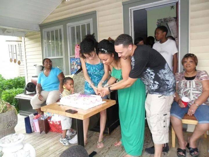 People enjoy a joyful gathering outside, sharing food and conversation on a warm day.