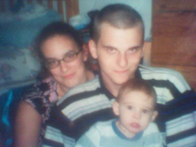 A couple poses with their baby in a warm indoor setting, showcasing family love and connection.