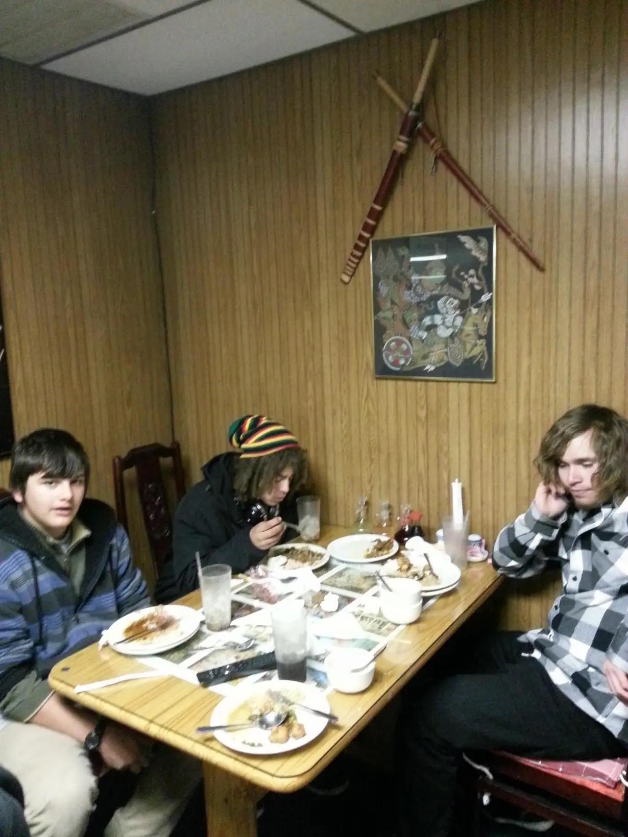 Three friends are gathered around a table filled with food, sharing stories and laughter.