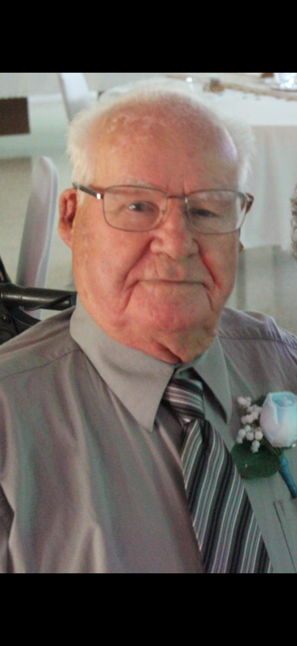 A senior man dressed in formal attire enjoys time with family at a daytime event.