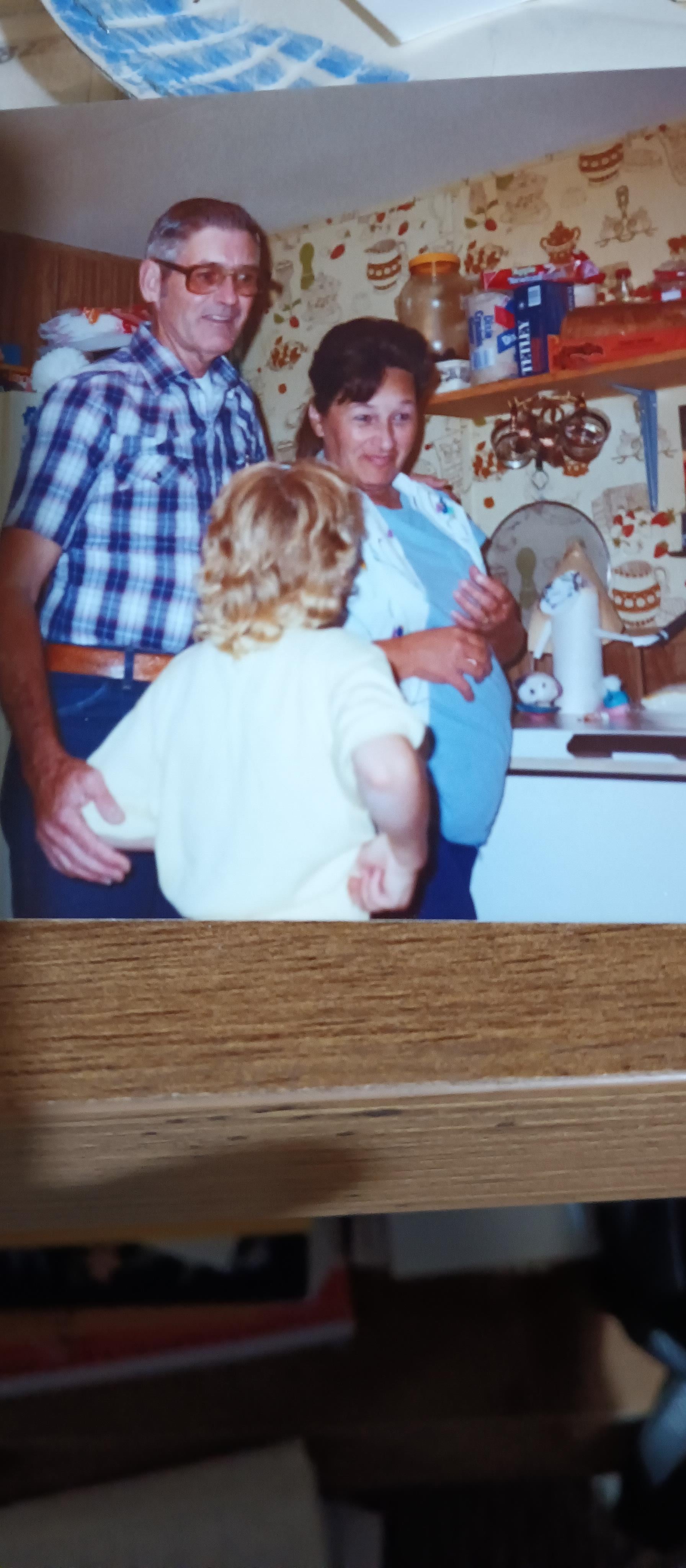 A child watches two adults cooking in a warm, vibrant kitchen filled with family love.