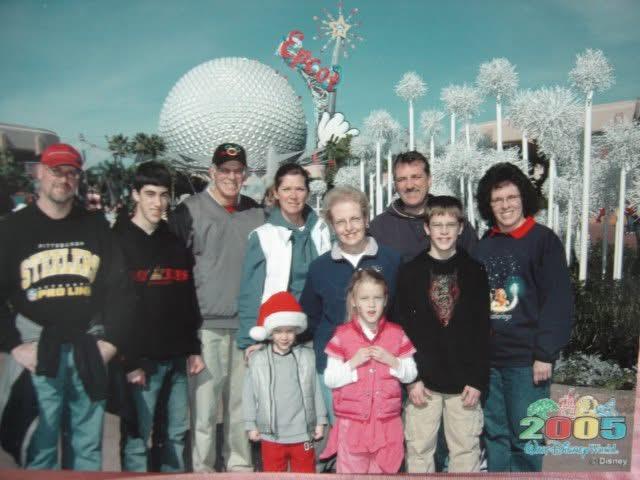 A family poses together in festive attire at a popular amusement park during winter.