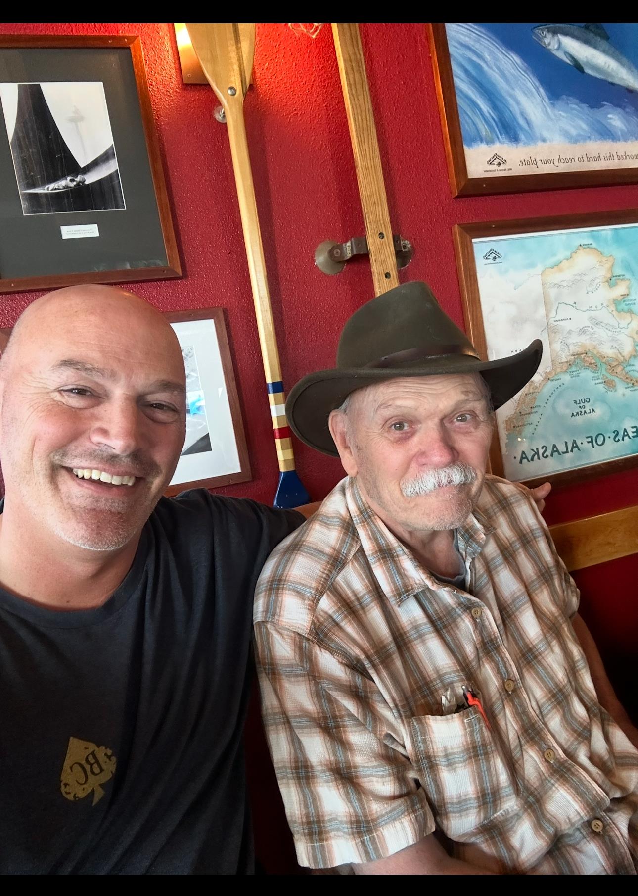 Two men sit together in a lively restaurant, enjoying each other's company and conversation.