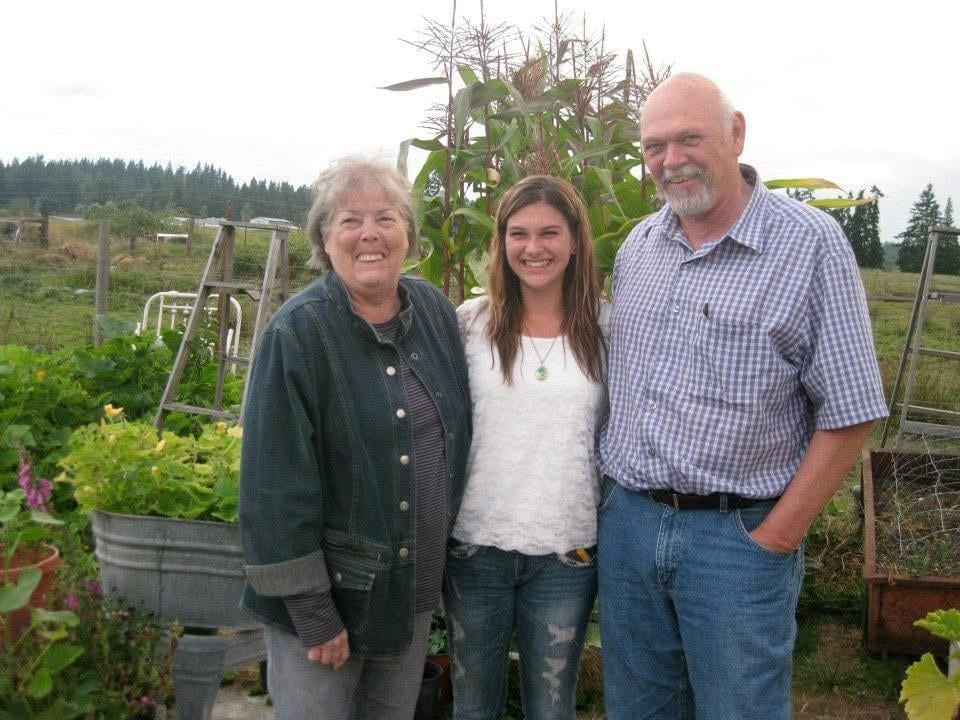 A joyful family moment in a lush garden with three people enjoying time together.