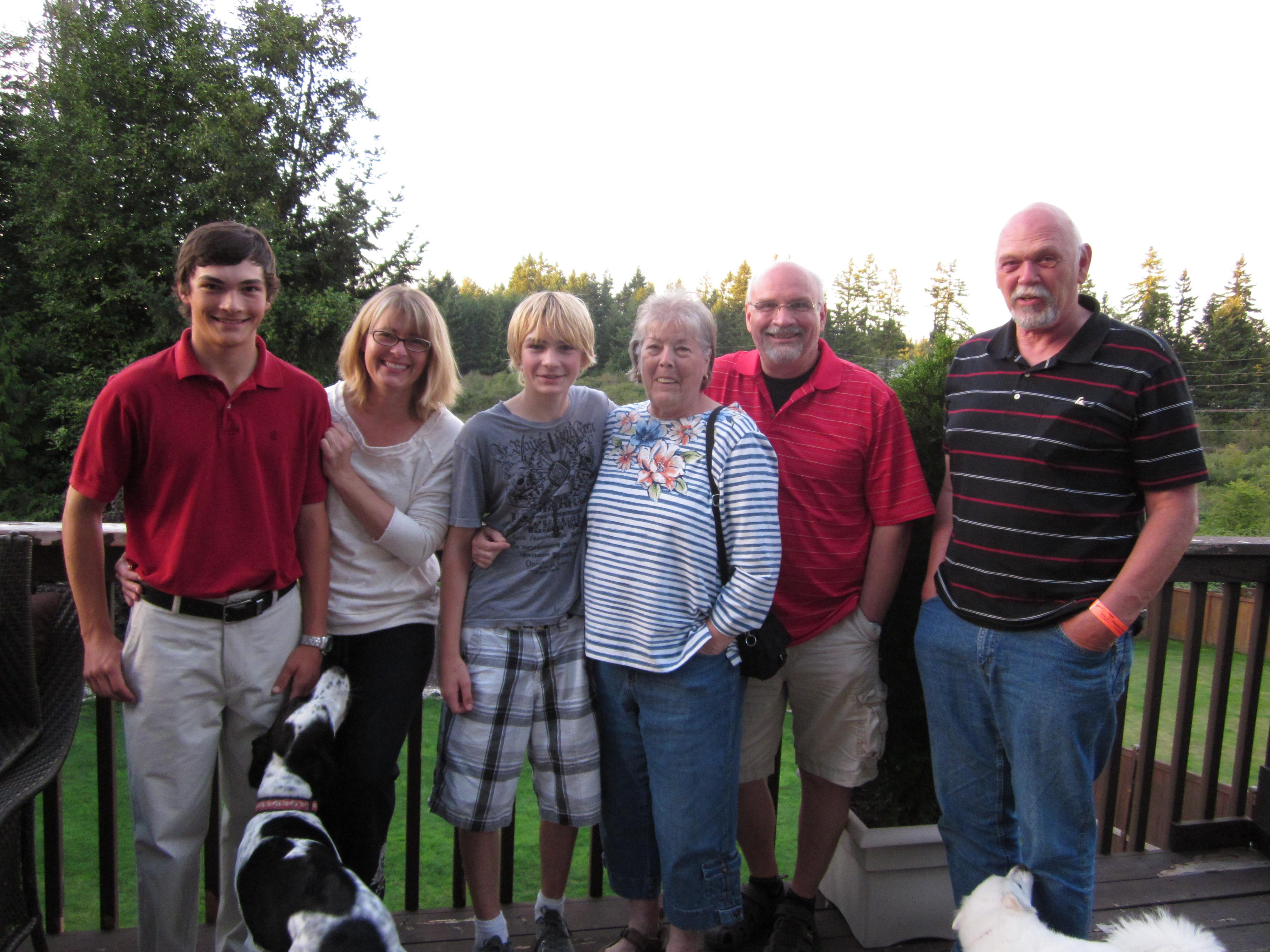 Family shares a sunset moment on a wooden deck, surrounded by nature.