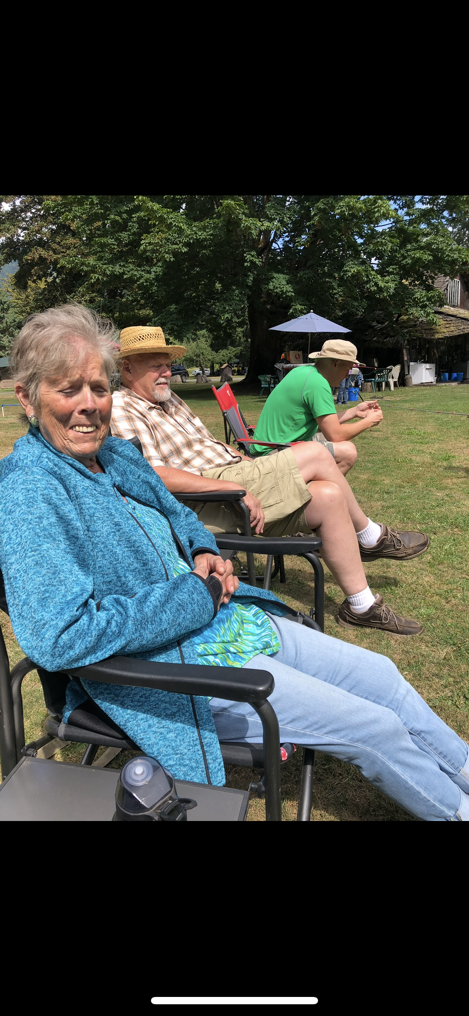 Seniors relax outdoors in the park, enjoying the sunshine and warm weather surrounded by greenery.