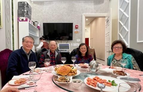 Friends and family enjoy a lively gathering around a beautifully set dining table filled with food.