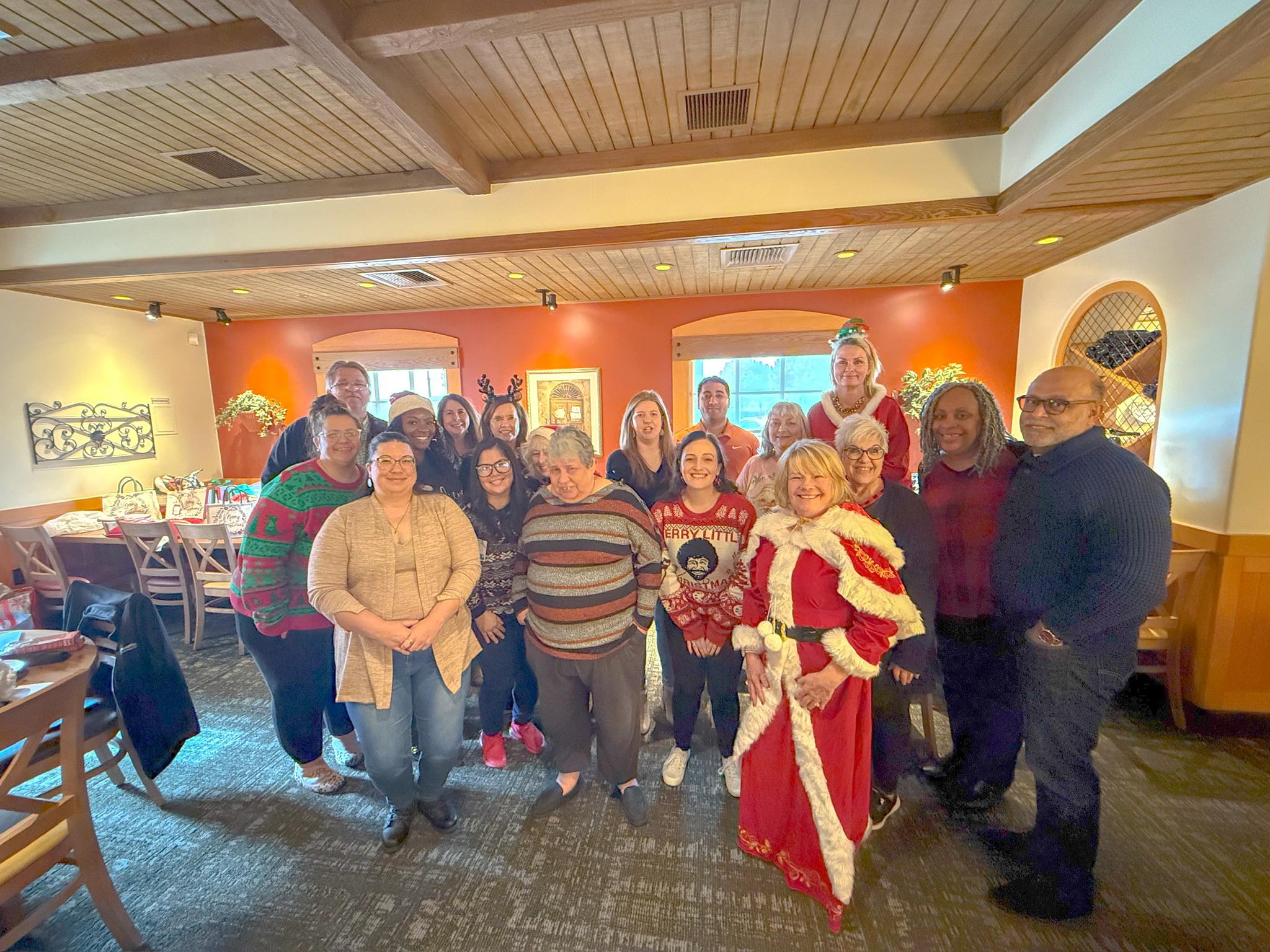 Cheerful group in holiday attire gathered in a cozy restaurant to celebrate together.