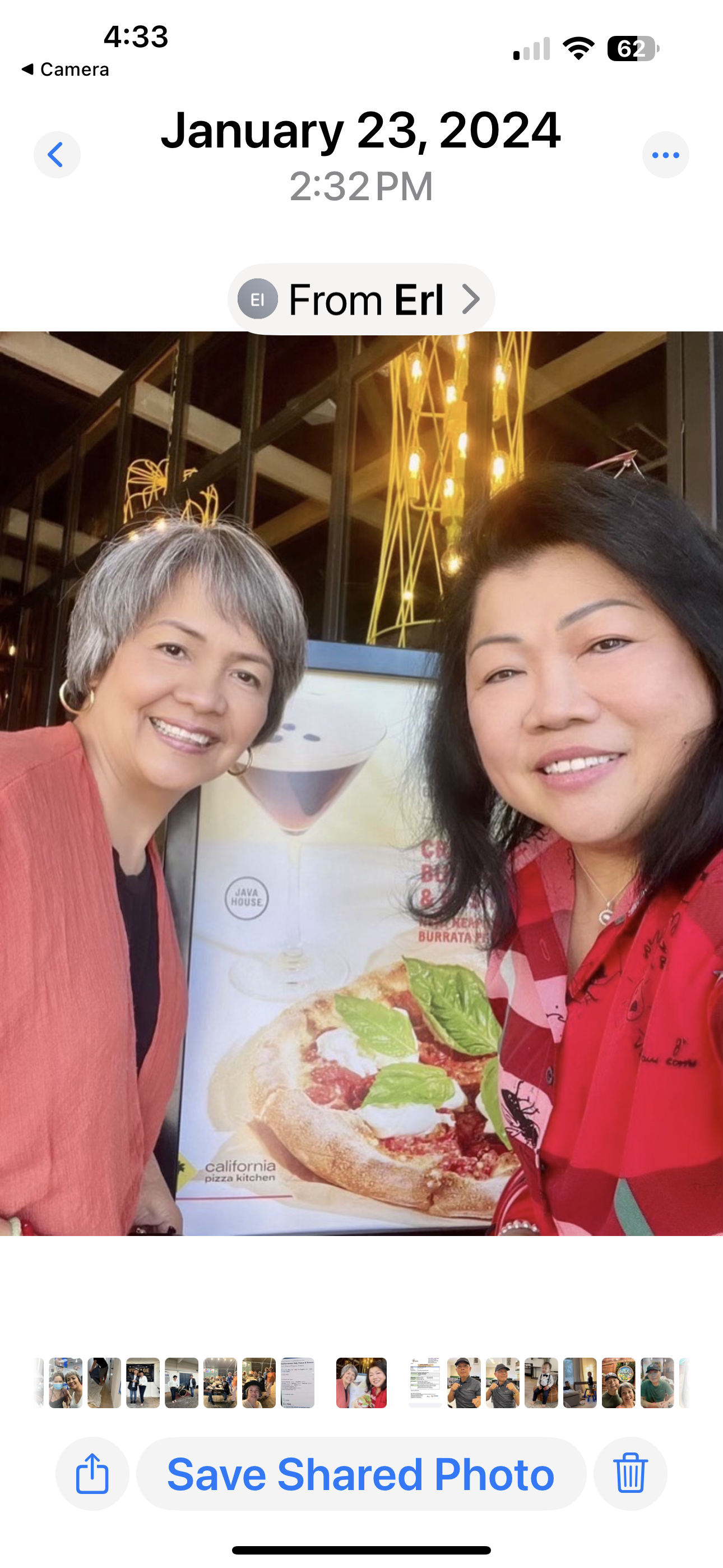 Two friends smiling and posing for a selfie outside a restaurant on a winter afternoon.