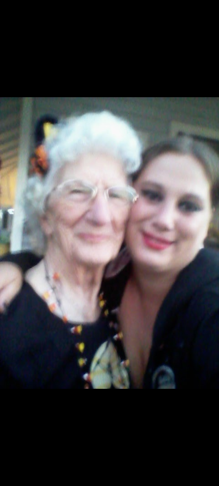 Two smiling women pose together outdoors, celebrating Halloween with festive attire and decorations.