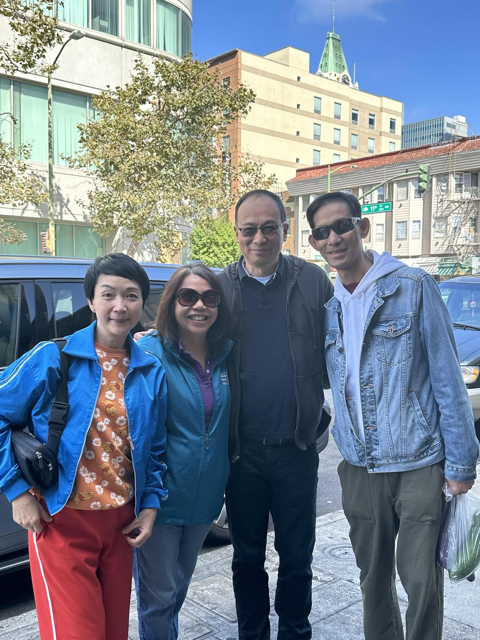 Four friends stand together on a lively street, enjoying the warm weather and good company.