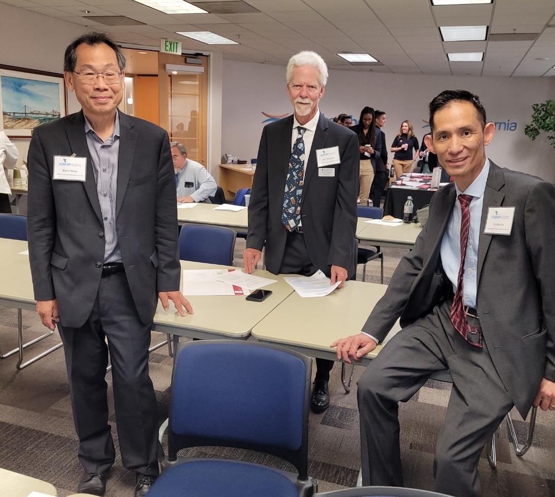 Three men in formal attire network and interact during a professional conference.
