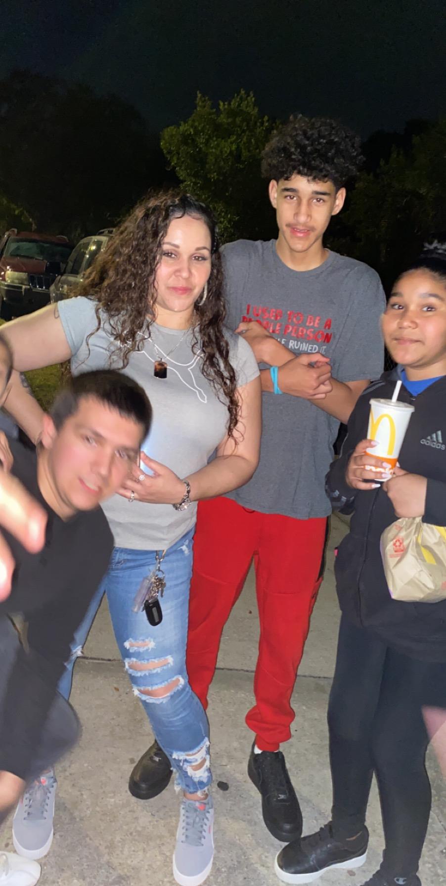 Friends laugh and pose together outdoors at night, enjoying each other's company.