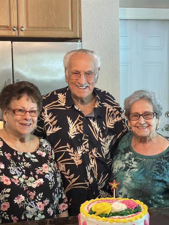 Joyful celebration with three friends enjoying cake together in a warm kitchen.