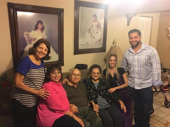 Family members smile and pose together in a warm living room adorned with portraits.