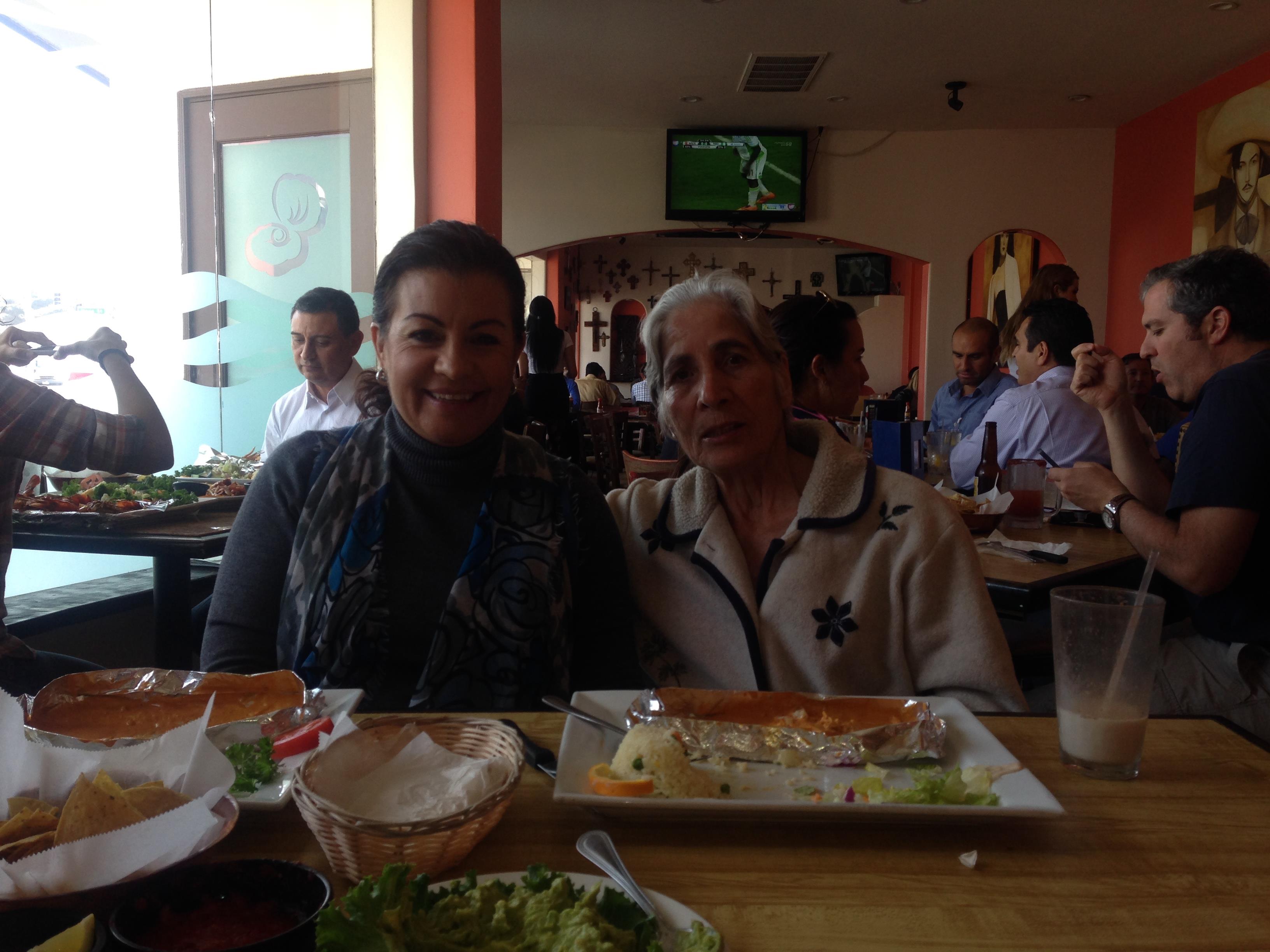 Two friends share a joyful moment over a delicious lunch in a crowded eatery.
