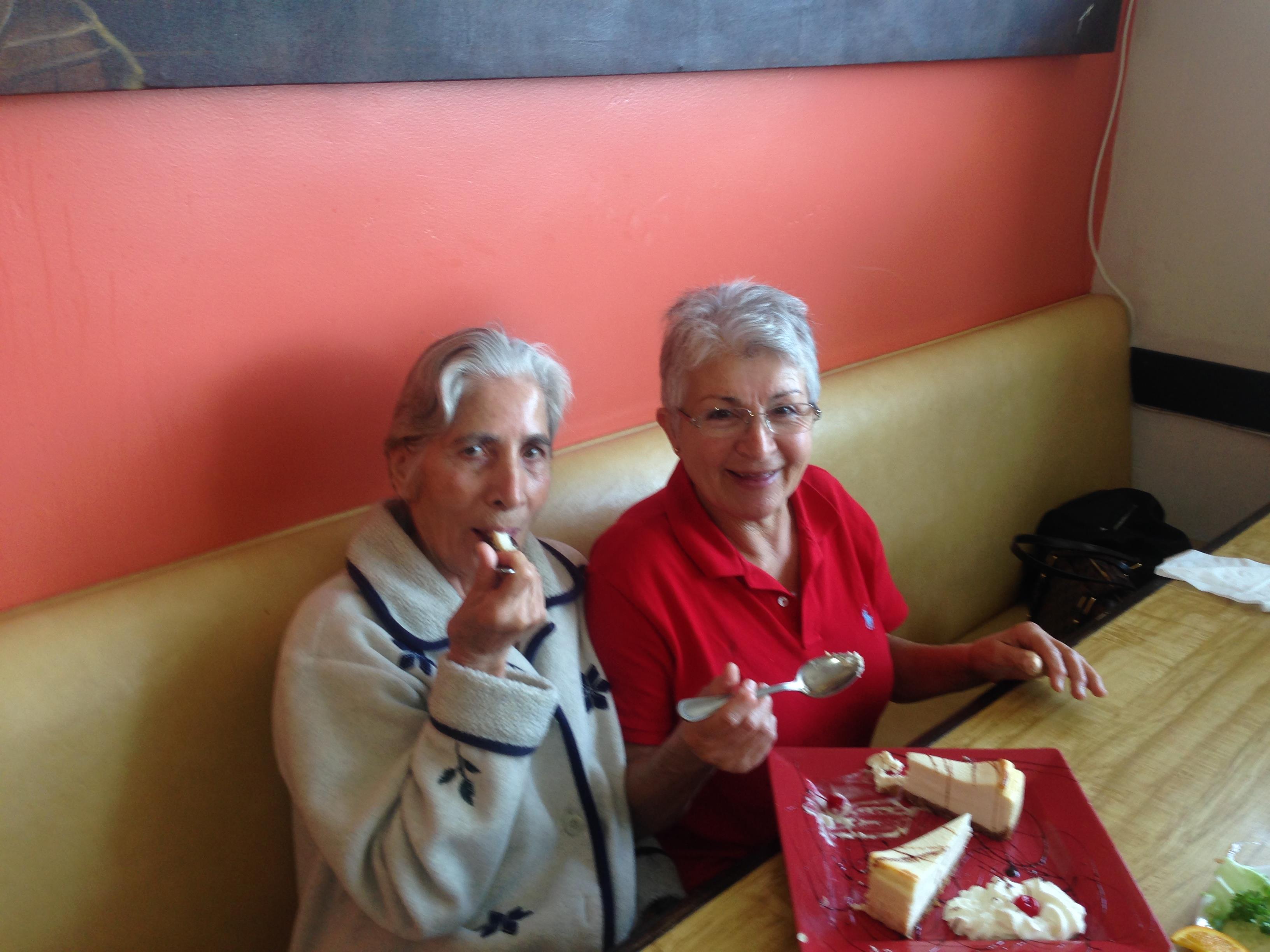 Two seniors sit at a table, happily sharing a meal and enjoying each other's company.