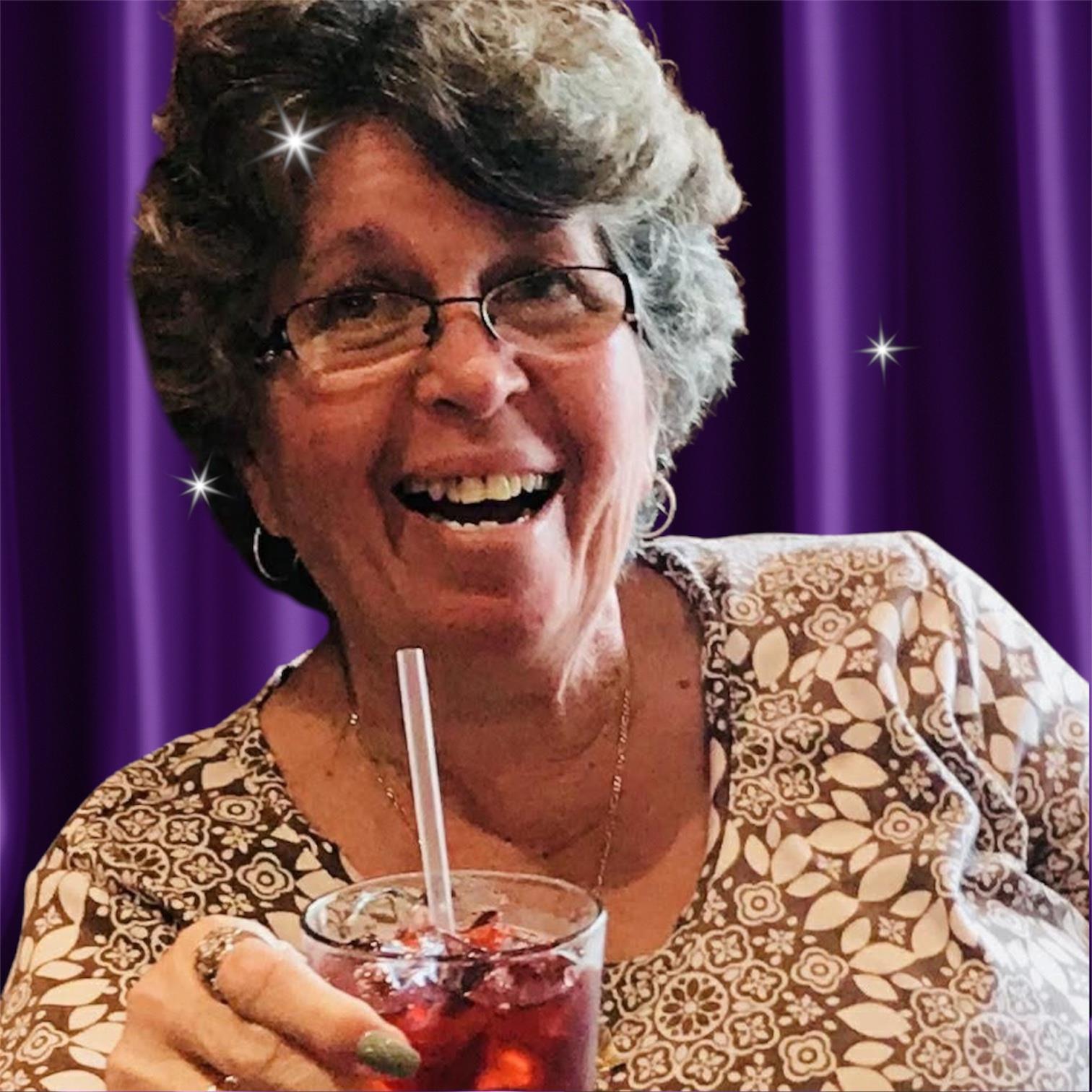 Woman smiles brightly while holding a colorful drink, surrounded by a warm and inviting atmosphere.
