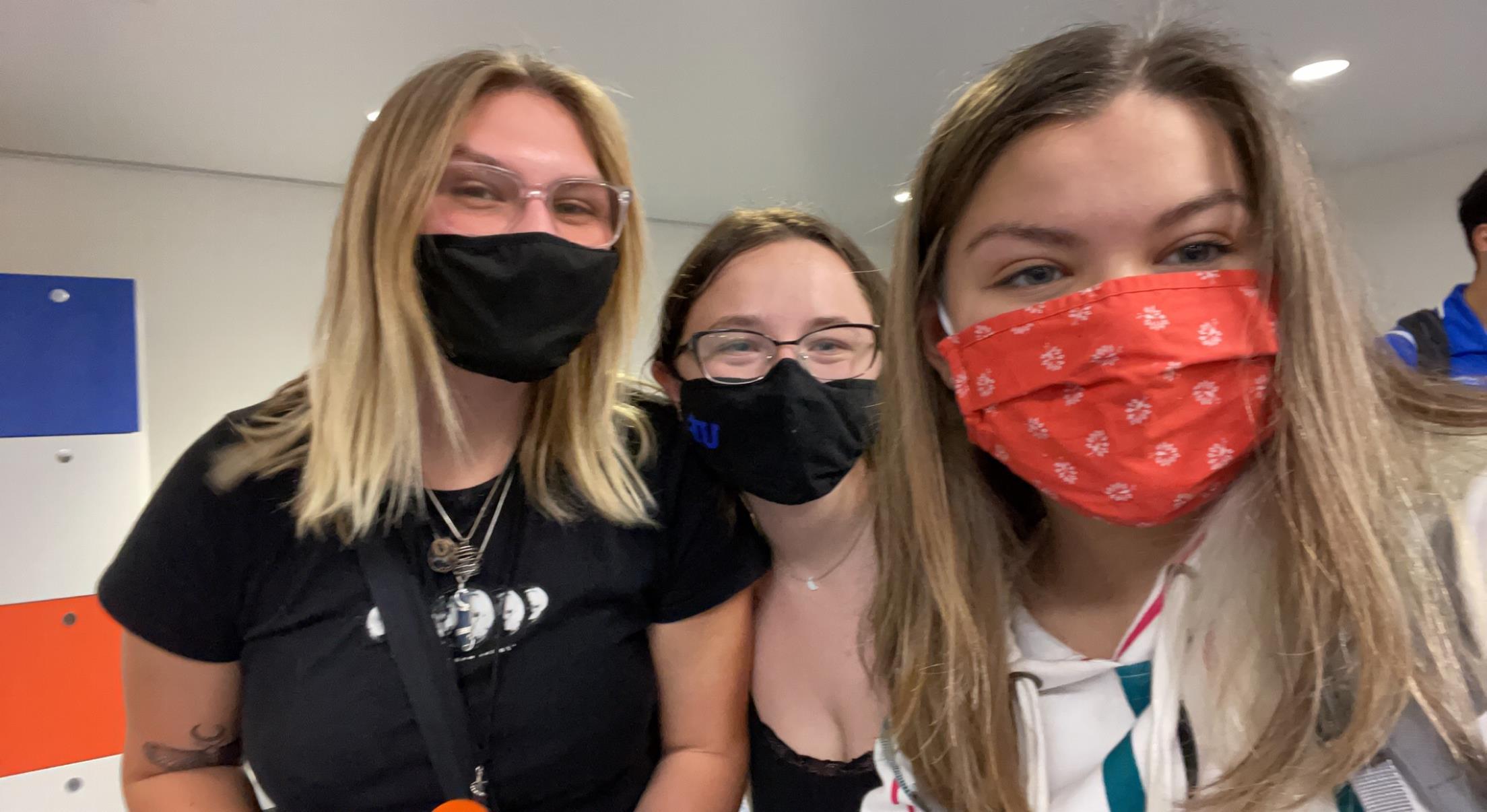 Friends gather together for a joyful moment, wearing vibrant masks and smiling happily.