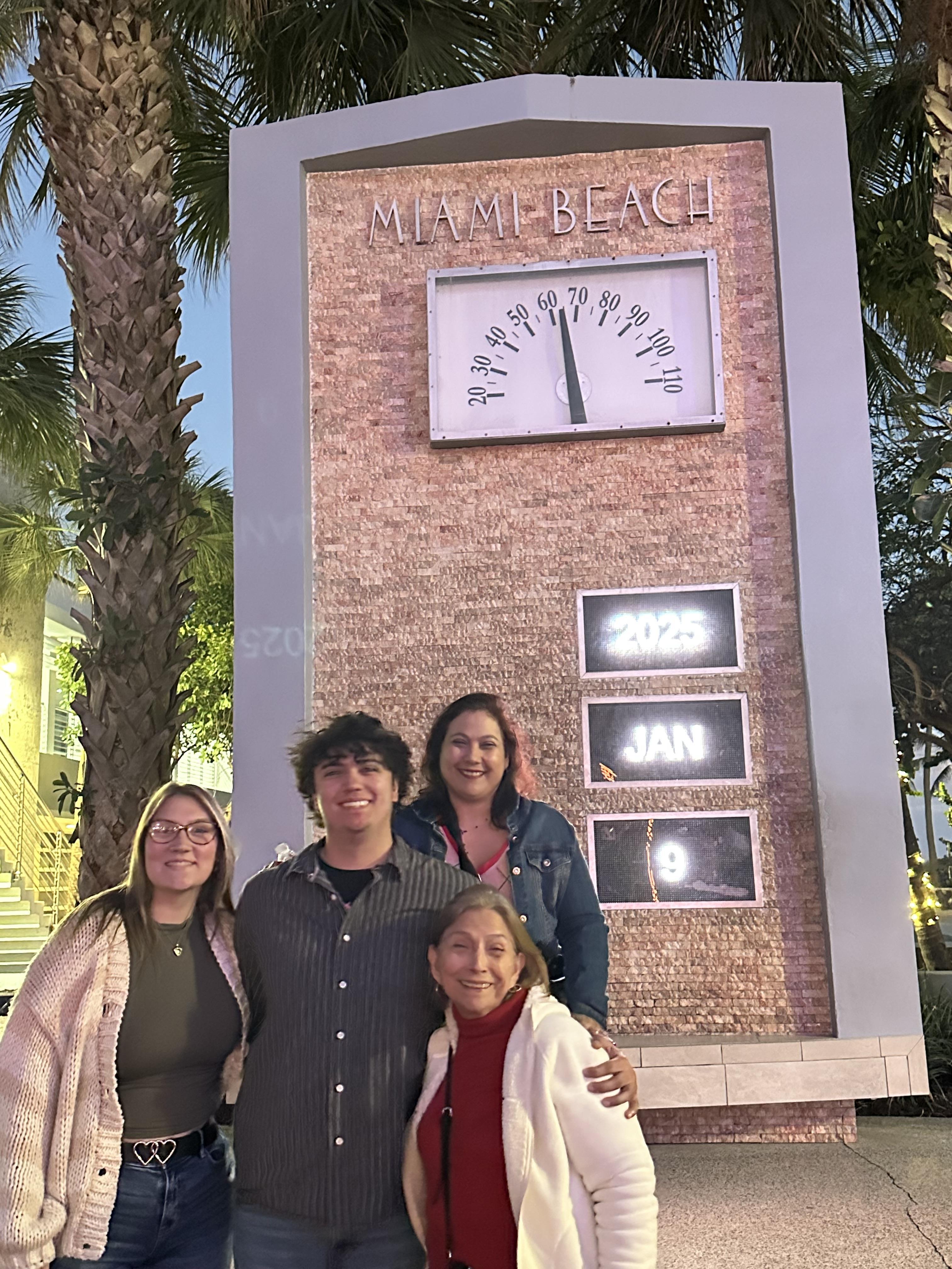 A group poses joyfully in front of a Miami Beach clock, marking the beginning of a new year.