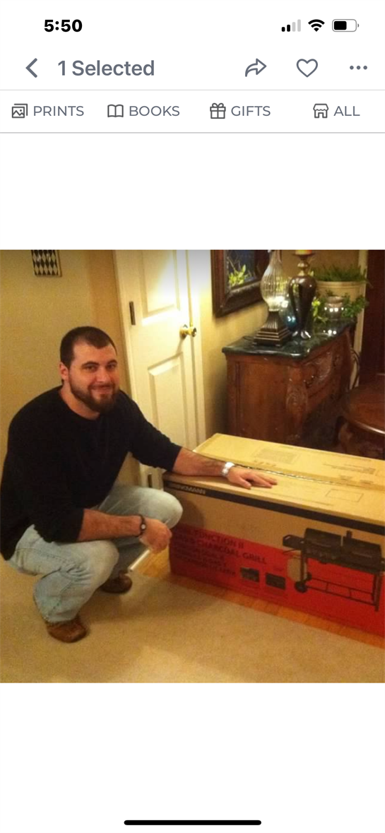 A man is crouched next to a sizable package in a cozy room with stylish decor.