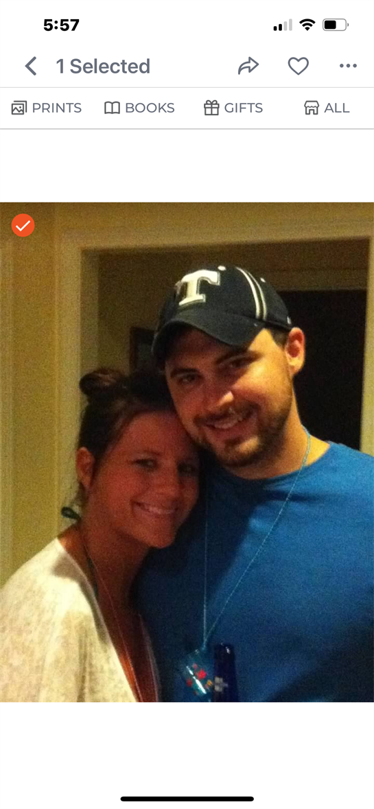 Two people smile together in a warm atmosphere, enjoying a joyful moment at a gathering.