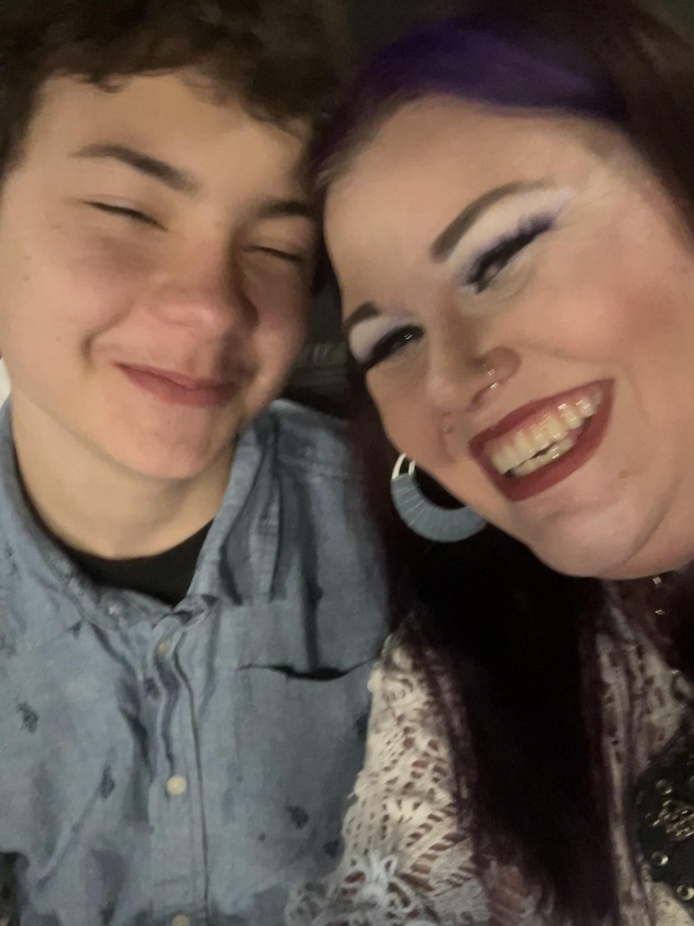 Two friends are smiling and enjoying each other's company at a casual evening event.