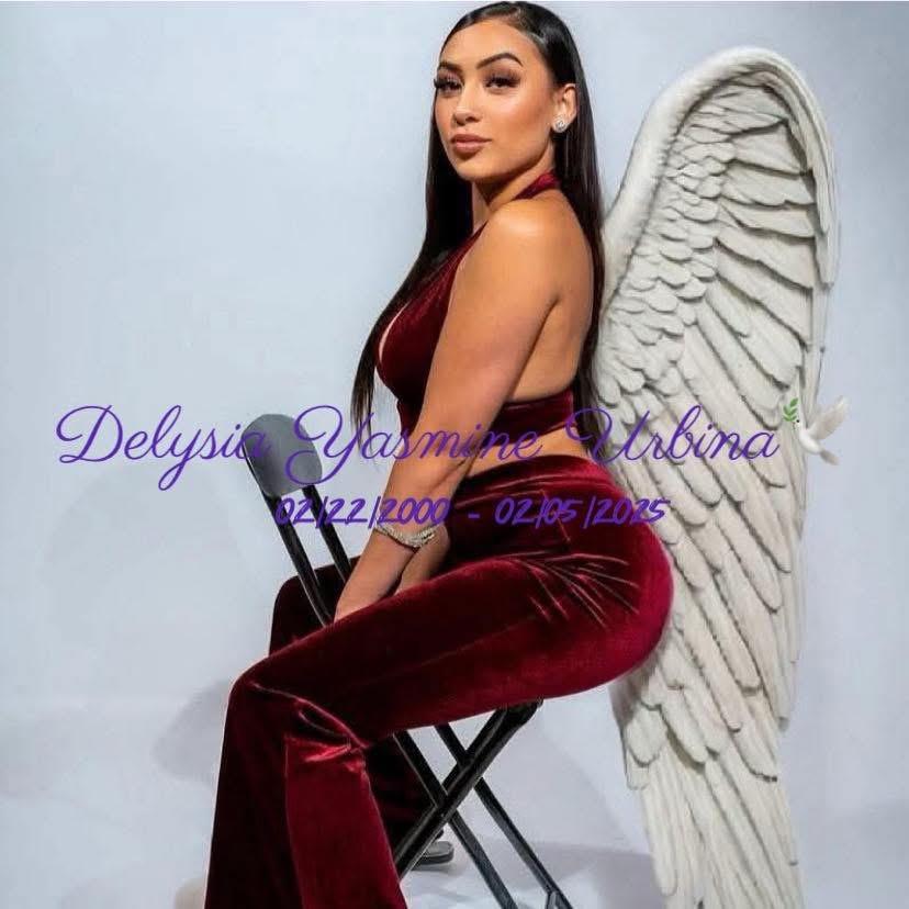 A confident young woman poses dramatically while wearing a stylish burgundy outfit with angel wings.