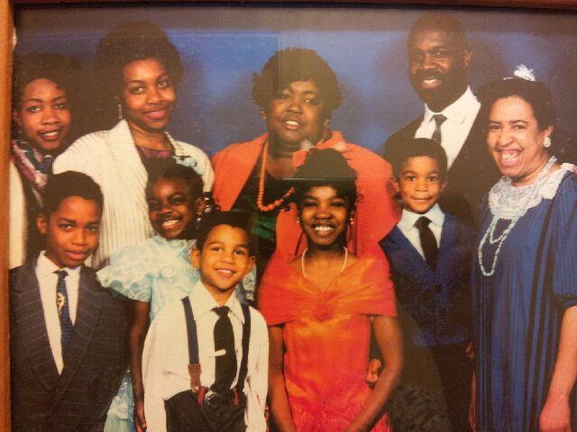 A large group of individuals dressed in formal attire share smiles and laughter at a family event.