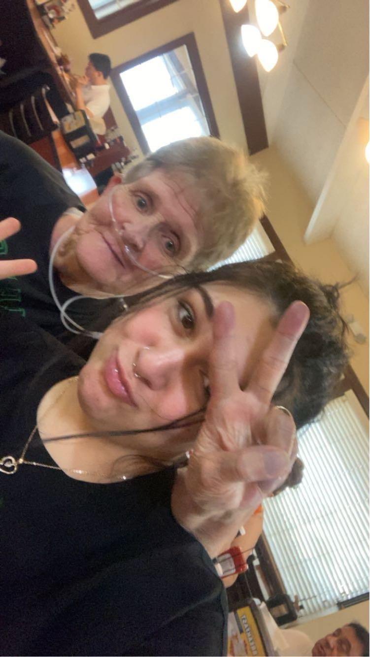 Two women smile happily, making peace signs as they enjoy their time together in a restaurant.