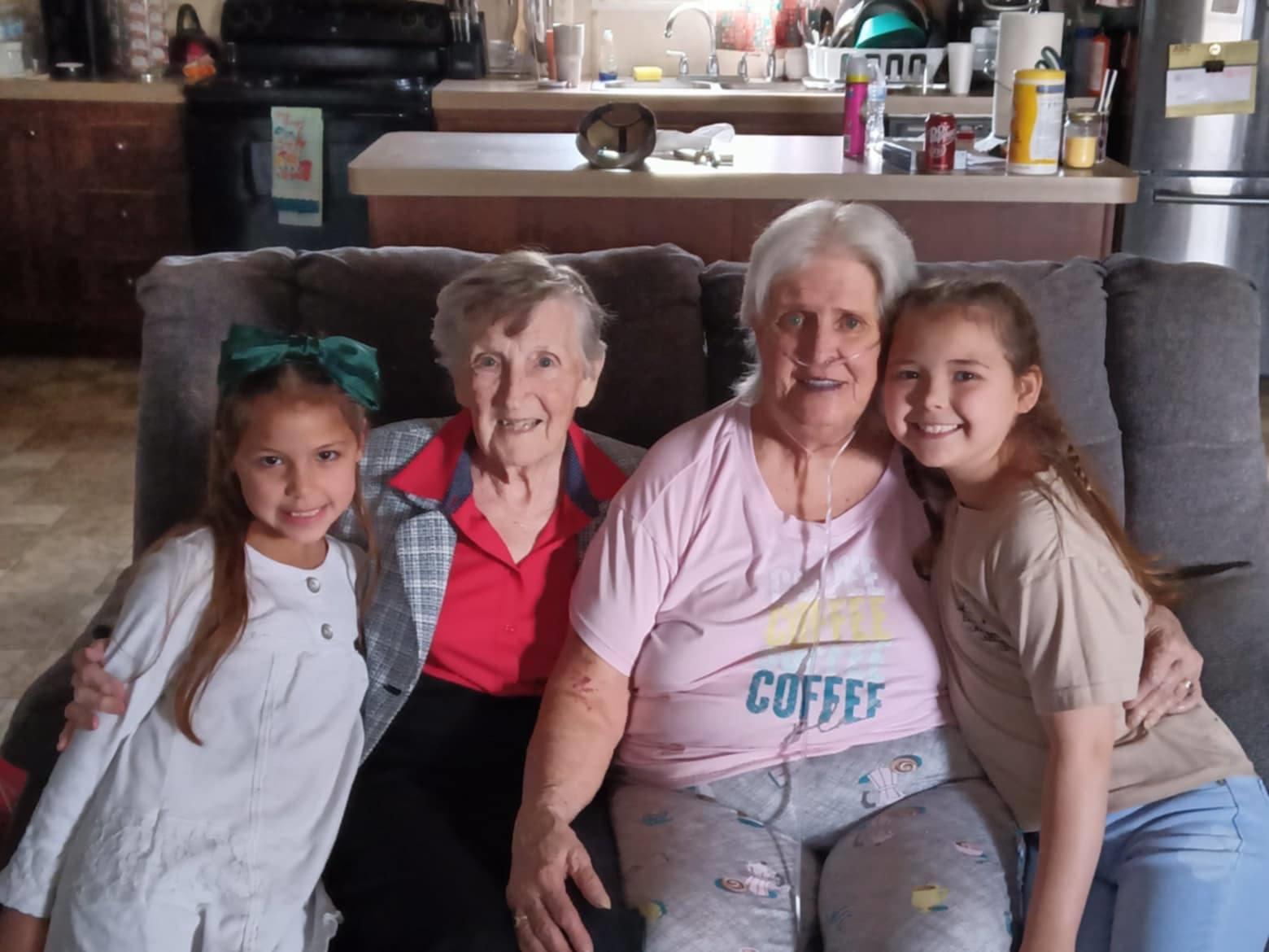 Four women of various ages relax and enjoy time together on a cozy couch.