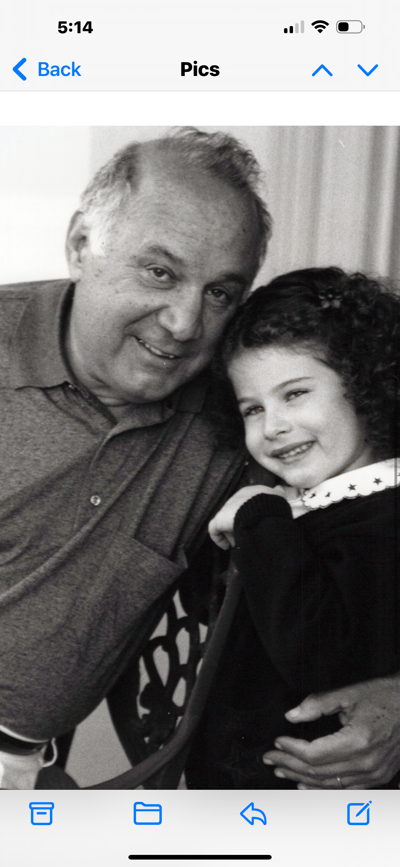 An elderly man embraces his granddaughter with a warm smile in a relaxed atmosphere.