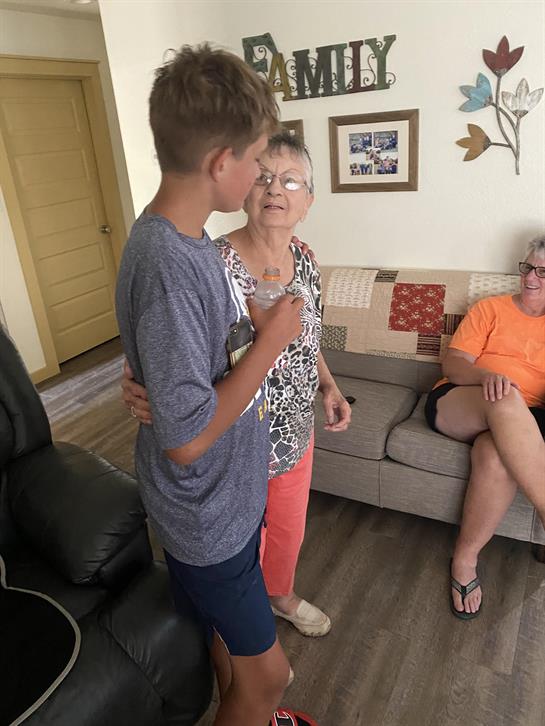 A boy hugging an old woman in a living room