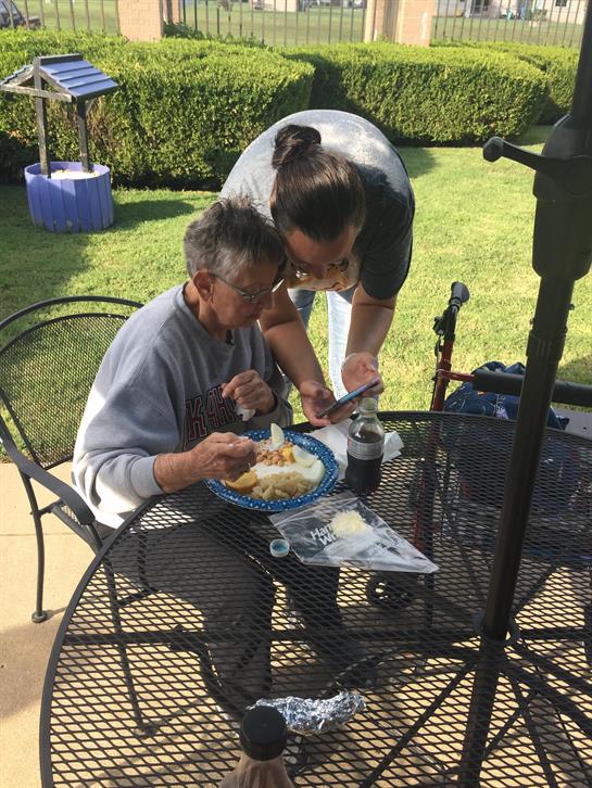 A woman helping an old man eat at a table
