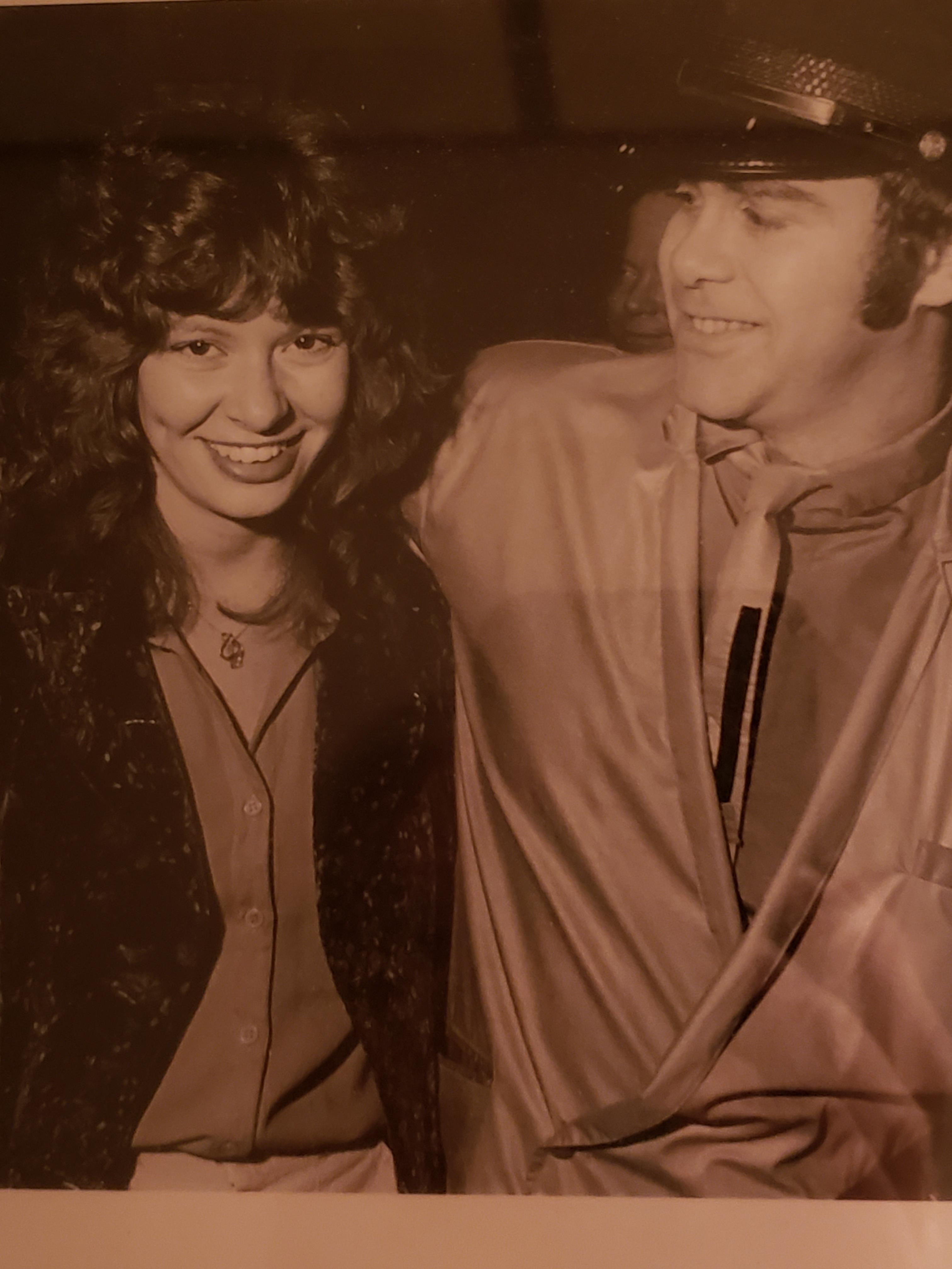 A joyful couple engages with one another while dressed in stylish vintage clothing.