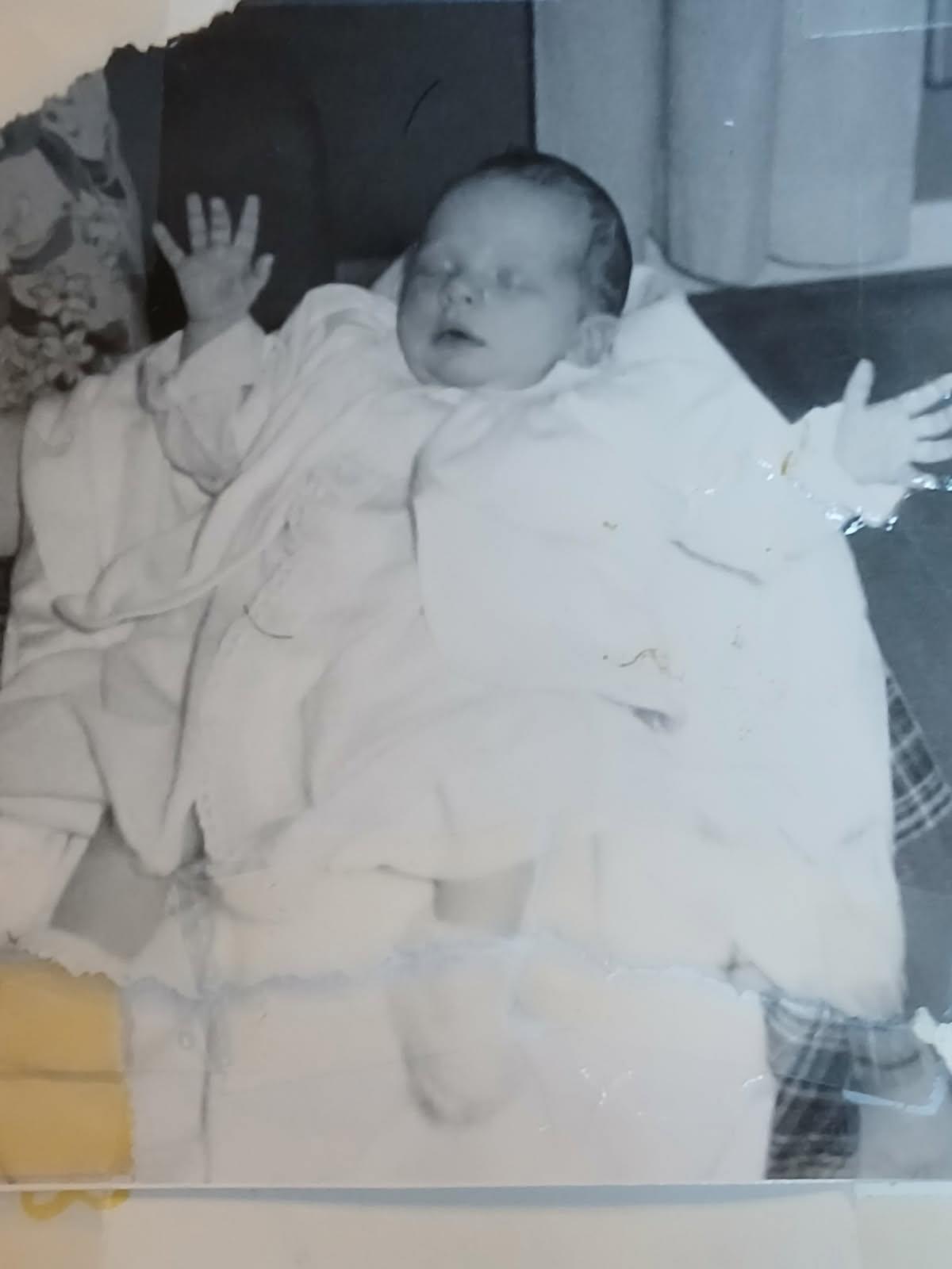 A child dressed in white happily waves to a gathering, creating a warm atmosphere.
