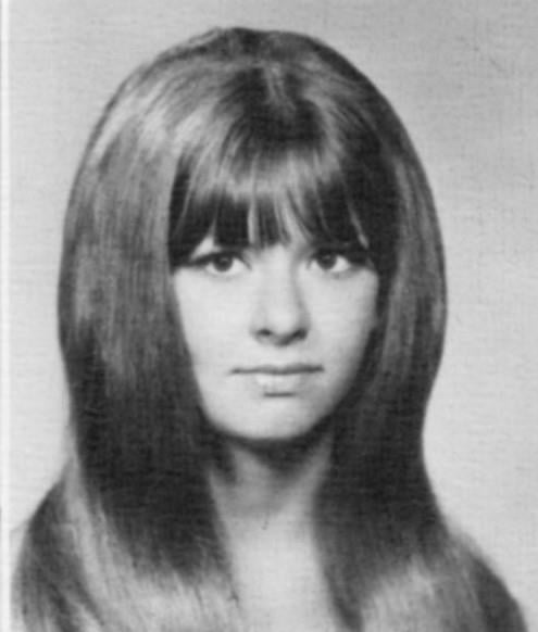 A young woman with long hair and bangs poses for a vintage-style school portrait.