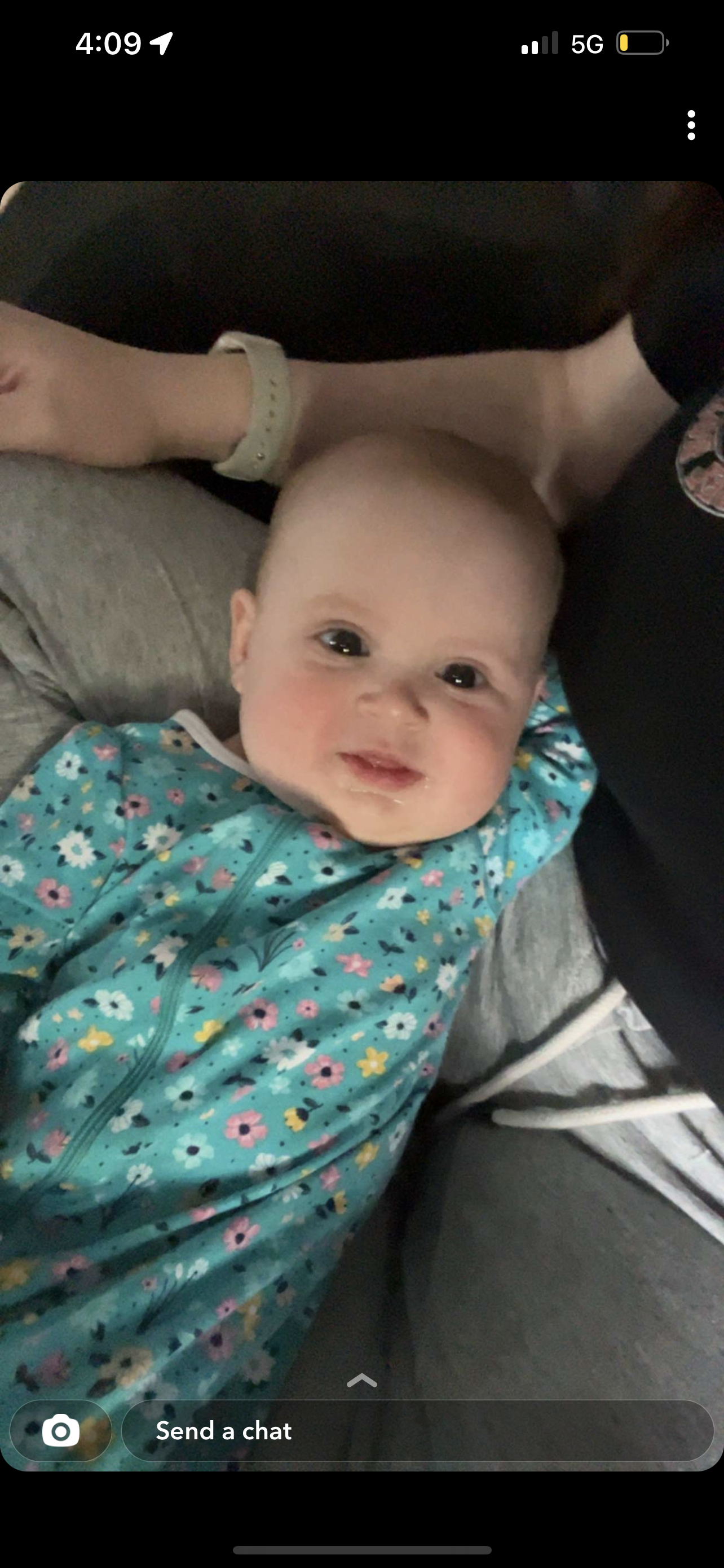 Infant joyfully gazes at the camera while being cradled comfortably.