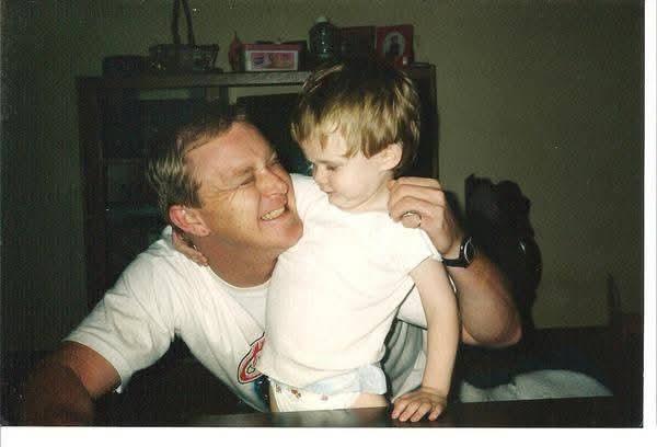 A father shares a playful moment with his son, enjoying laughter while at home.