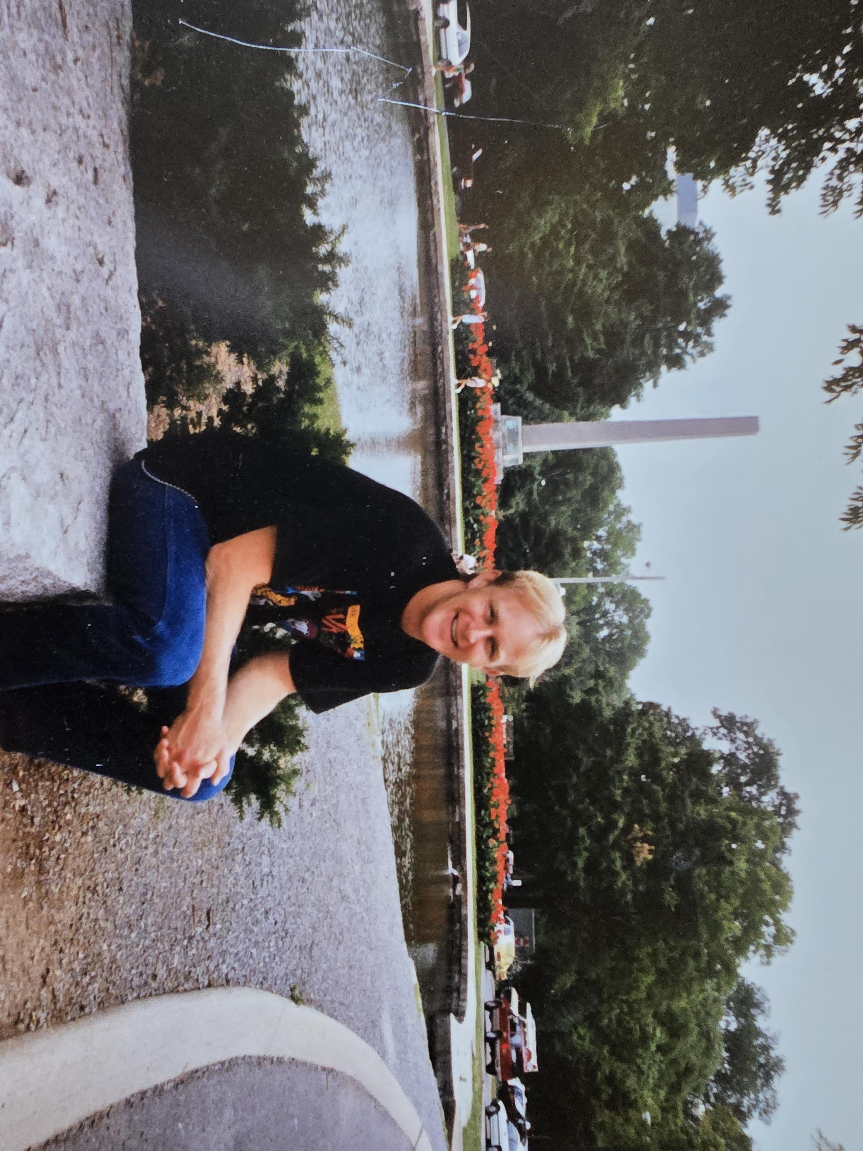 Individual enjoys a peaceful moment near a fountain surrounded by lush greenery.