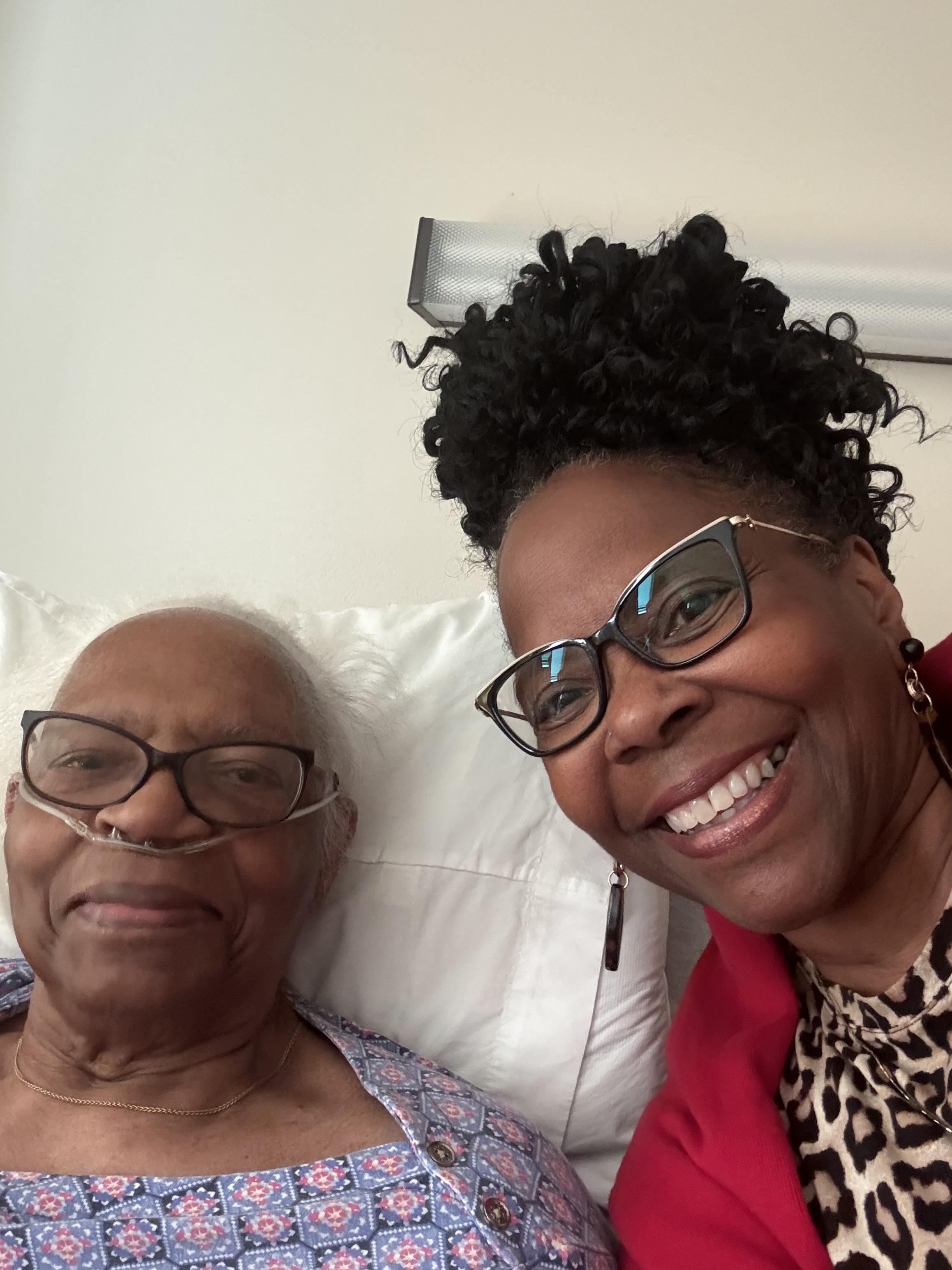 A caregiver shares a joyful moment with an elderly patient in a hospital bed.