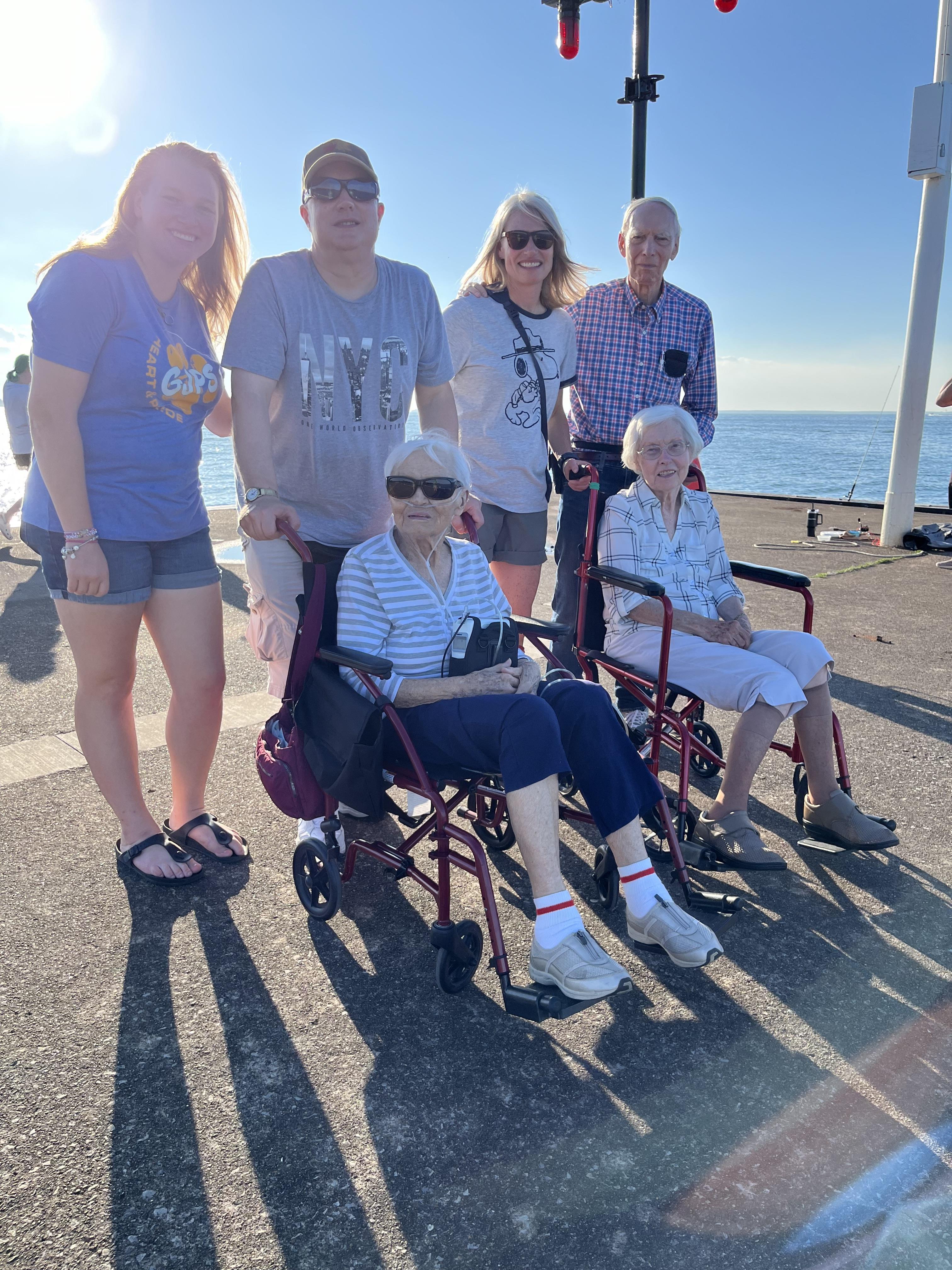 Group of six family members gathered at a beachside location on a sunny day.