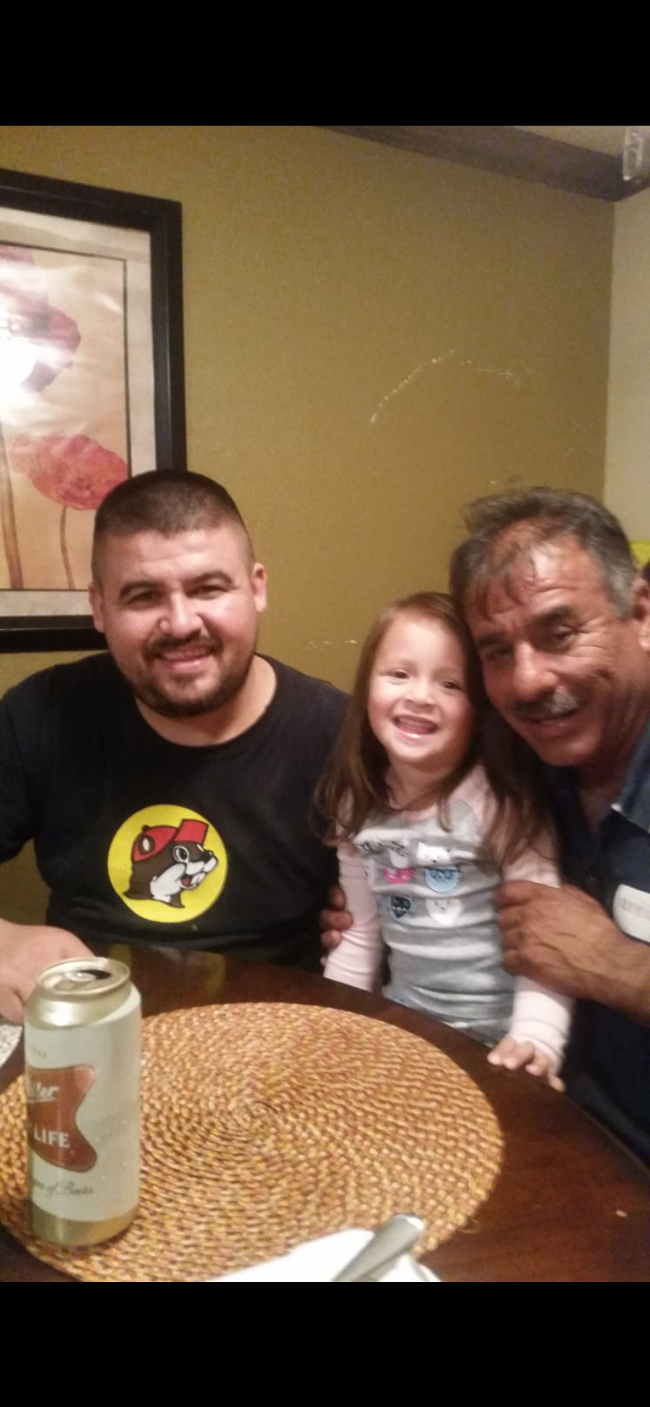 A cheerful child poses with two adults at a table filled with love and laughter.