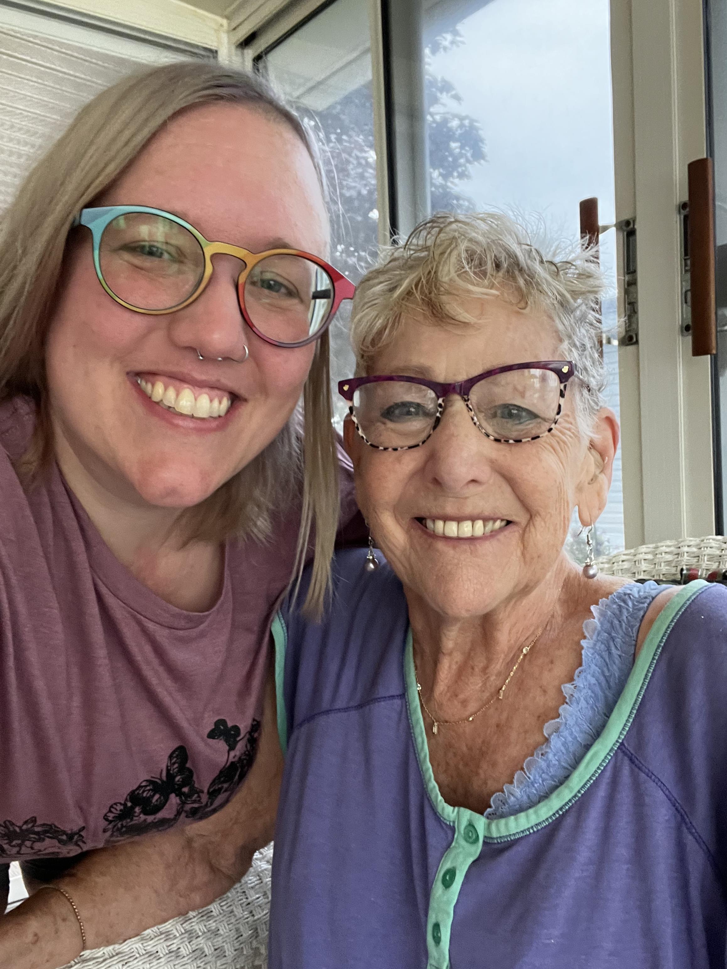 Two women share a joyful moment together, surrounded by natural light and warmth.