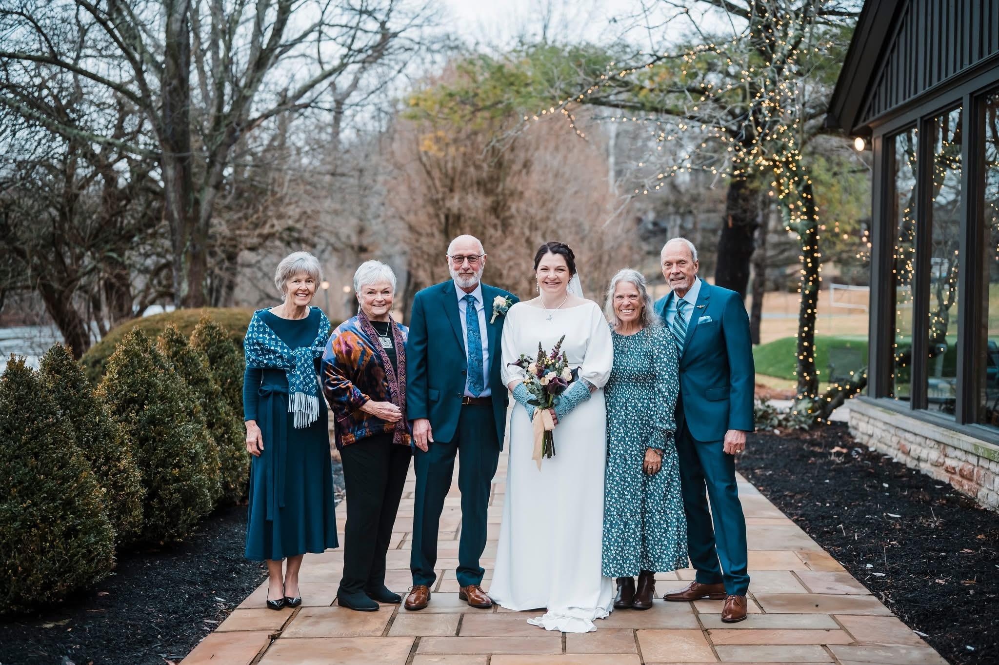 Loved ones celebrate a wedding, posing together outside in a charming early spring landscape.