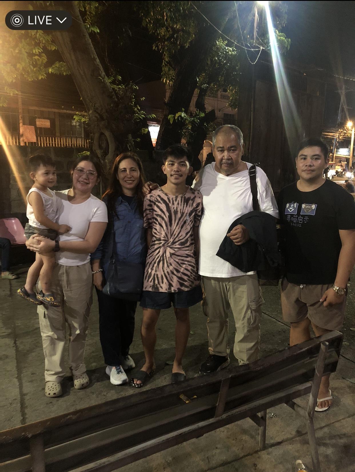 Family members gather under streetlights, smiling and enjoying their time together in the evening.